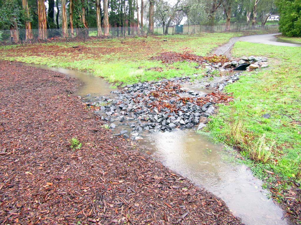 Stone-lined drainage channel directing water across a slope