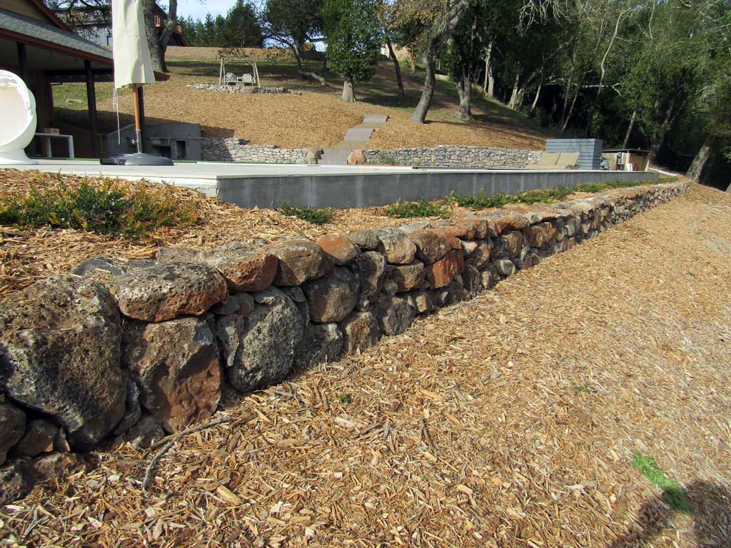 Fieldstone wall forming a pool-side planter
